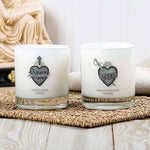 Two white candles with religious designs on a woven mat.