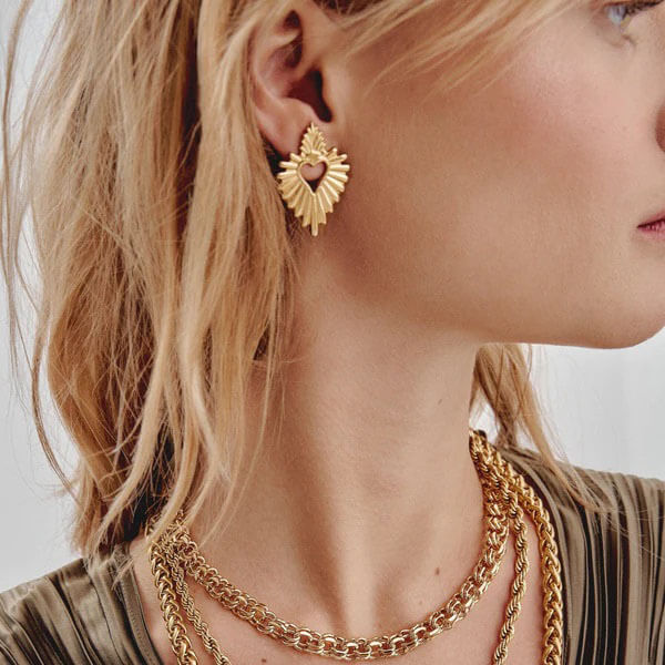 Close-up of a woman wearing gold hoop earrings and necklaces.