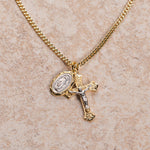 Gold necklace with a cross pendant on a beige surface.