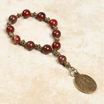 Bracelet with red beads and a gold charm on a beige background.