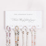 Set of rosary beads displayed on a holder with 'The Anderson Family' and 'Hail Mary full of grace' text on a white background.