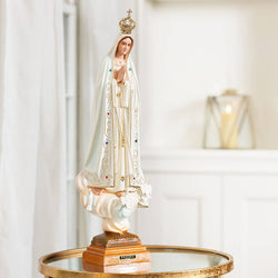 Statue of the religious figure, Fatima, with a crown on a reflective surface.