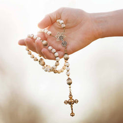 Hand holding a rosary with a blurred background