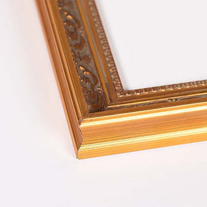 Close-up of an ornate gold picture frame corner with carved detailing, shown on a plain white background.