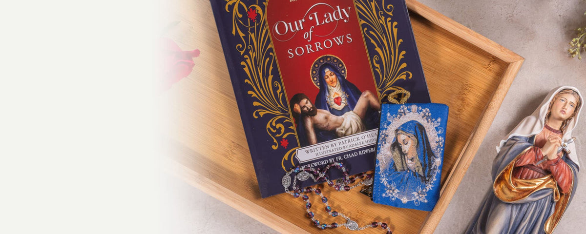 Religious items depicting Our Lady of Sorrows, including a Rosary, a book, and a statue, laid out on a wooden board.