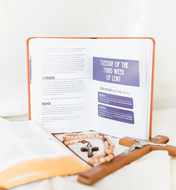 Open book with religious items on a white surface