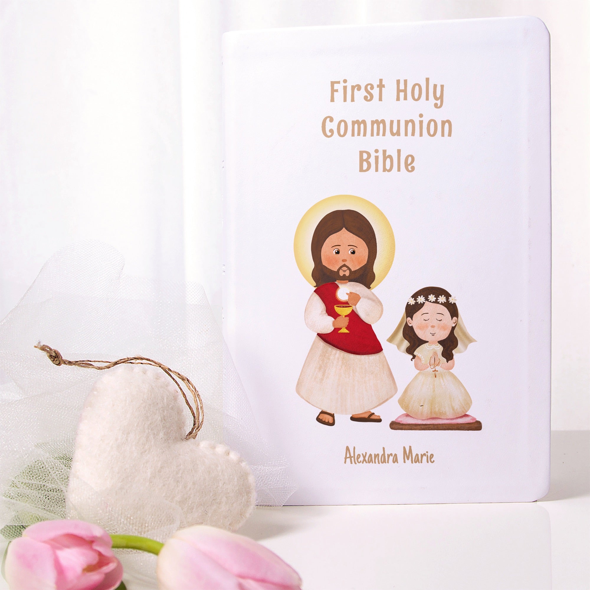 White, hard-cover Bible for First Communion featuring cartoon illustrations of Jesus and a girl in a white dress.