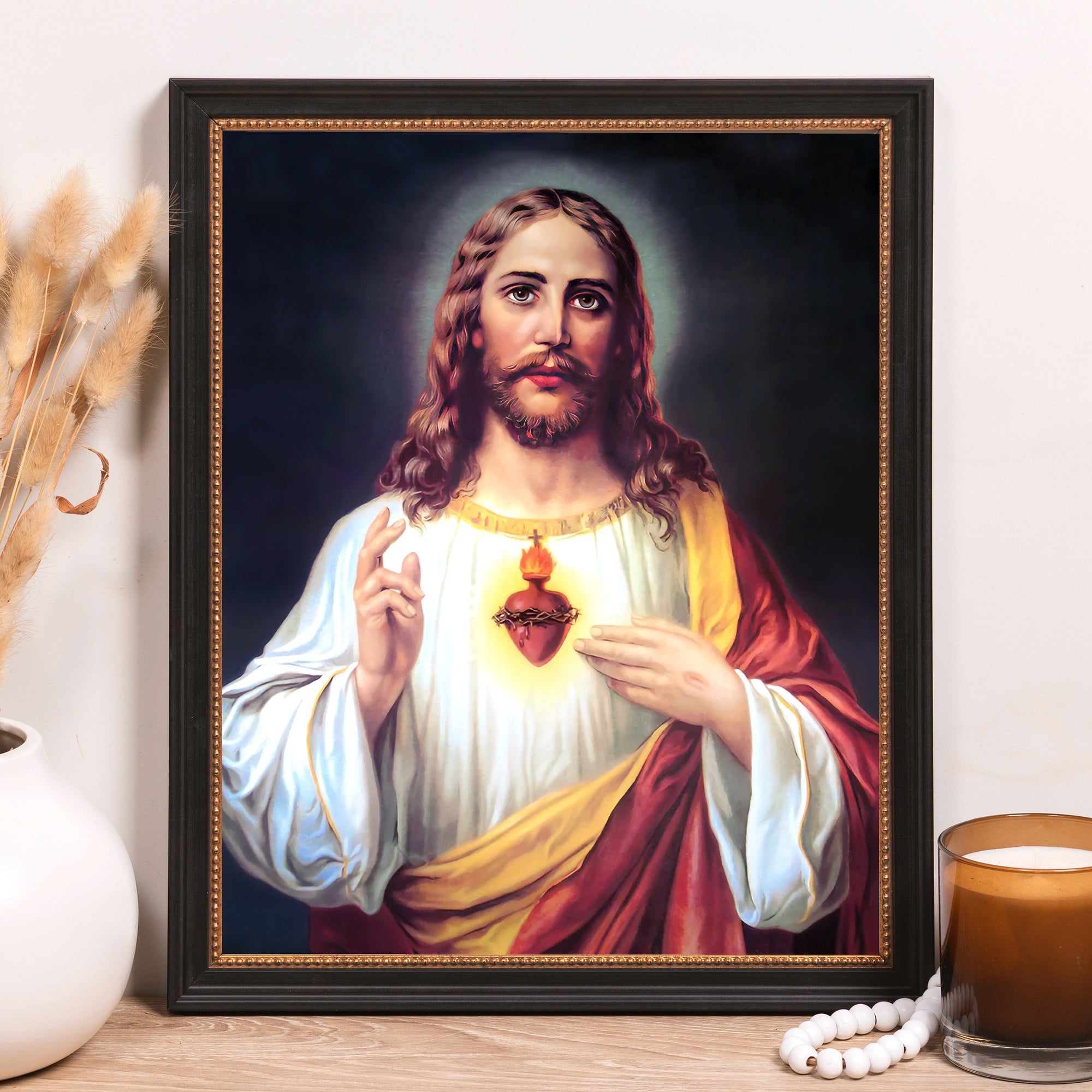 Framed portrait of Jesus with a sacred heart, with a black wood frame and gold trim.