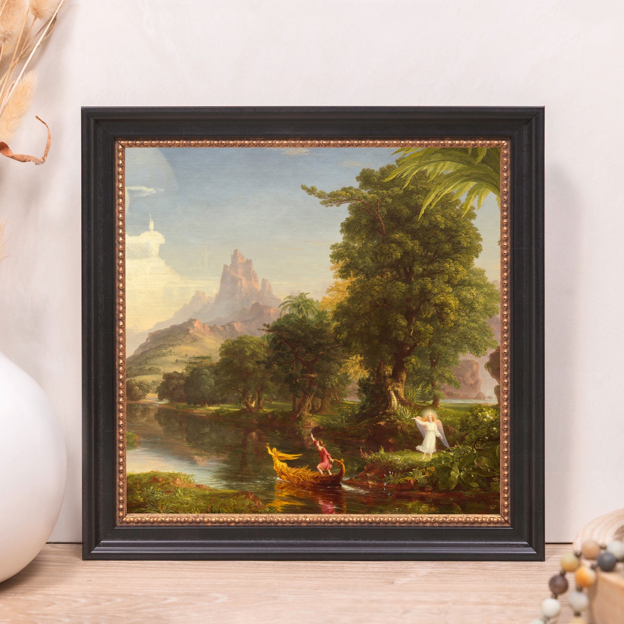 Framed Thomas Cole painting, "The Voyage of Life: Childhood," with black and gold frame depicting a landscape, river, and people.