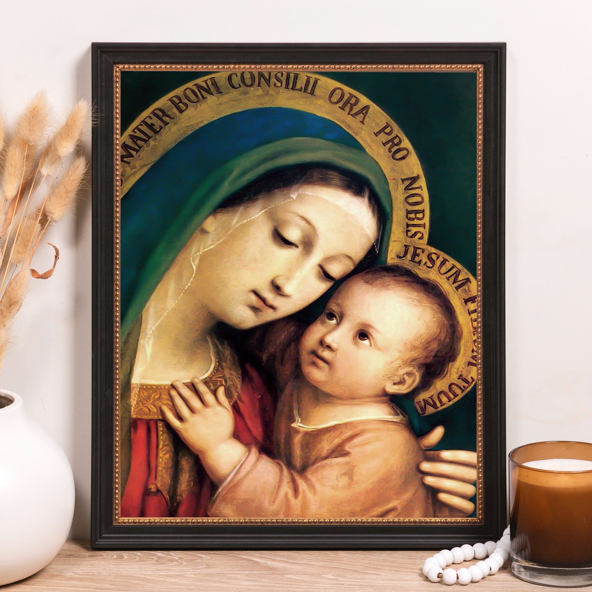 Framed painting of Madonna and Child in a dark frame with gold accents, displayed on a light wood surface.