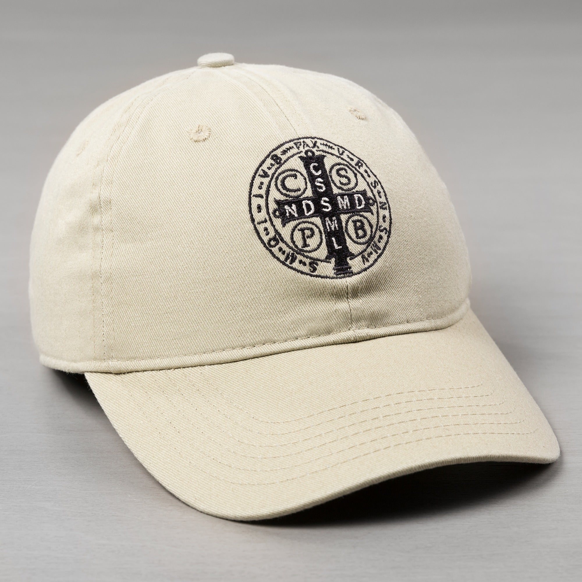 Khaki baseball cap with black embroidered St. Benedict medal on crown.