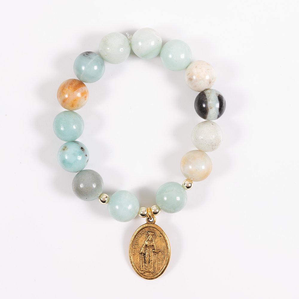 Beaded bracelet made of blue, grey, and tan stone beads with an oval gold pendant.