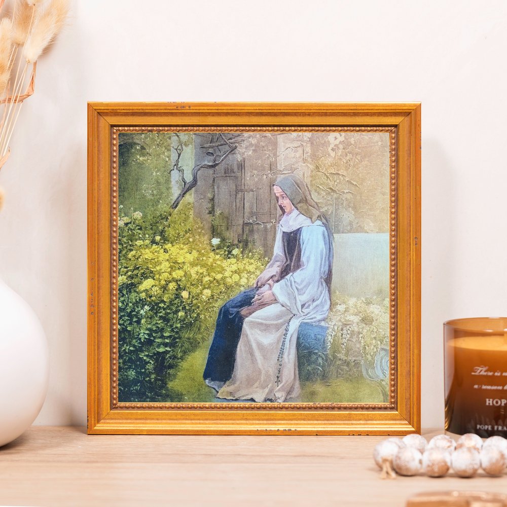 Framed print of a nun sitting, gold frame, classic style.