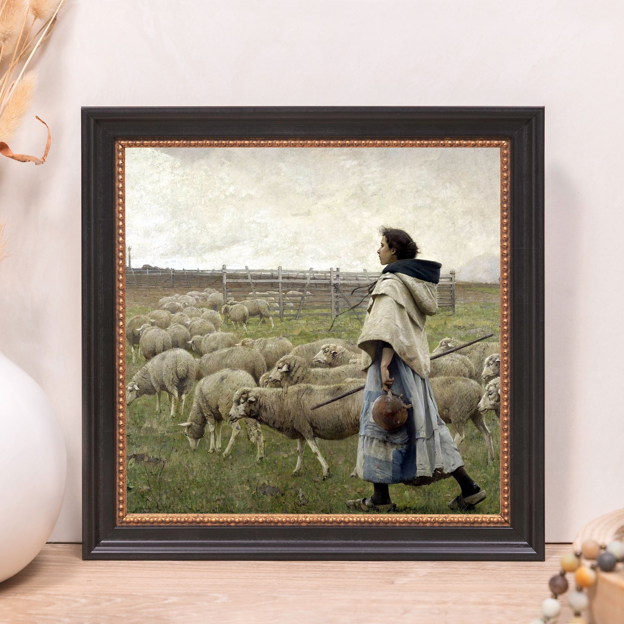 Framed art print of a girl herding sheep in a pastoral landscape with a black wood frame.