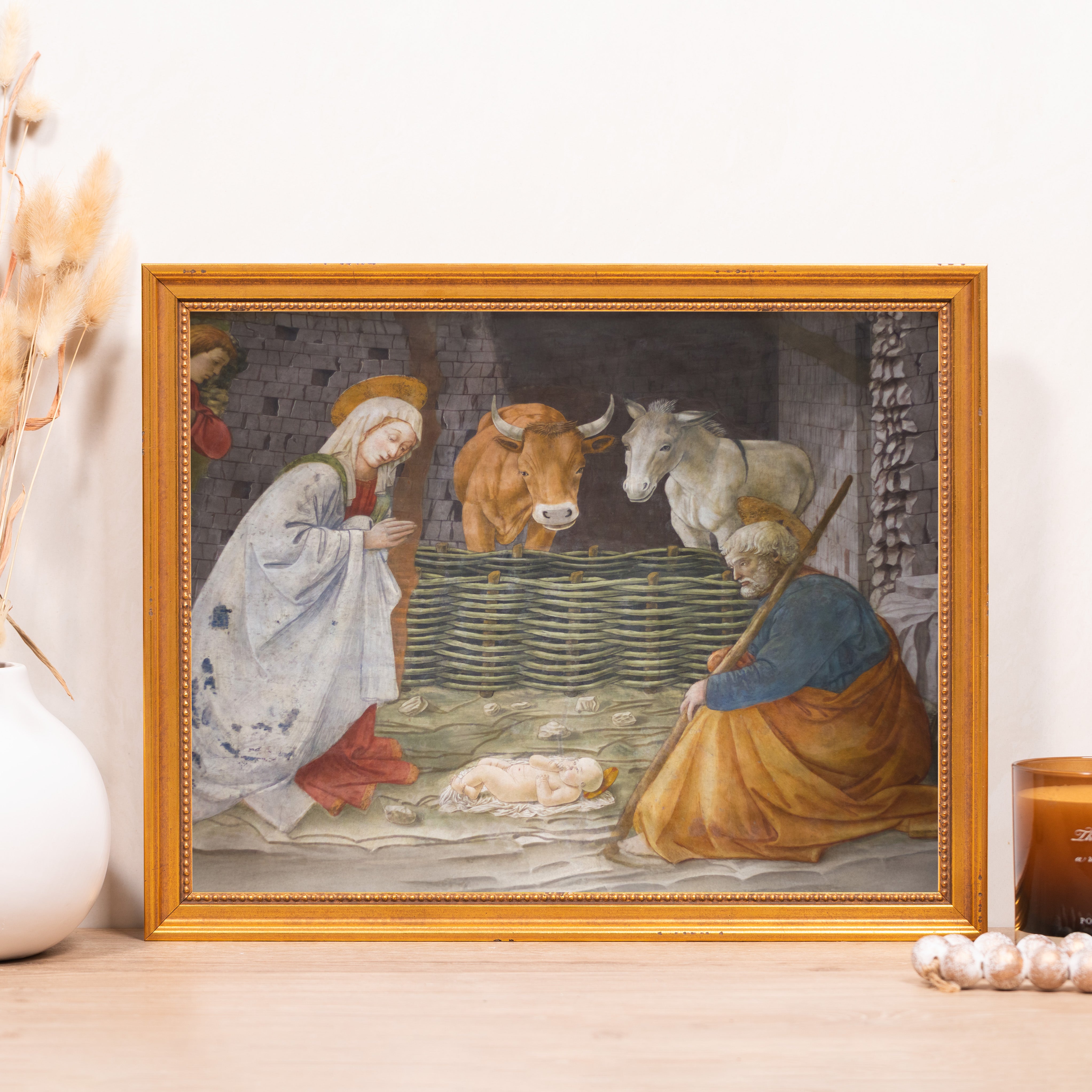 Framed Nativity art print with gold frame shows baby Jesus, Mary, Joseph, and animals.