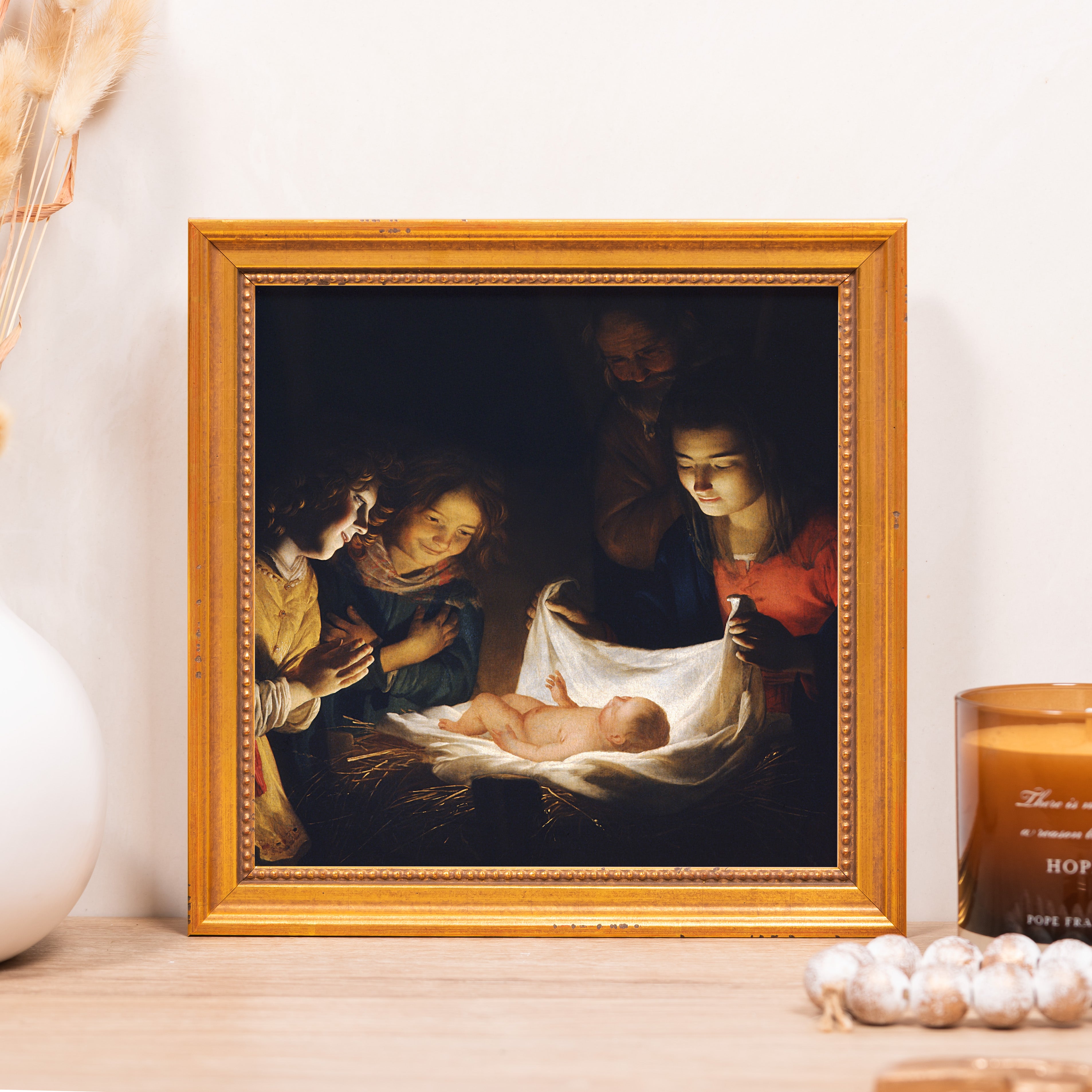 Framed print of the Nativity in gold frame shows baby Jesus surrounded by family and onlookers.