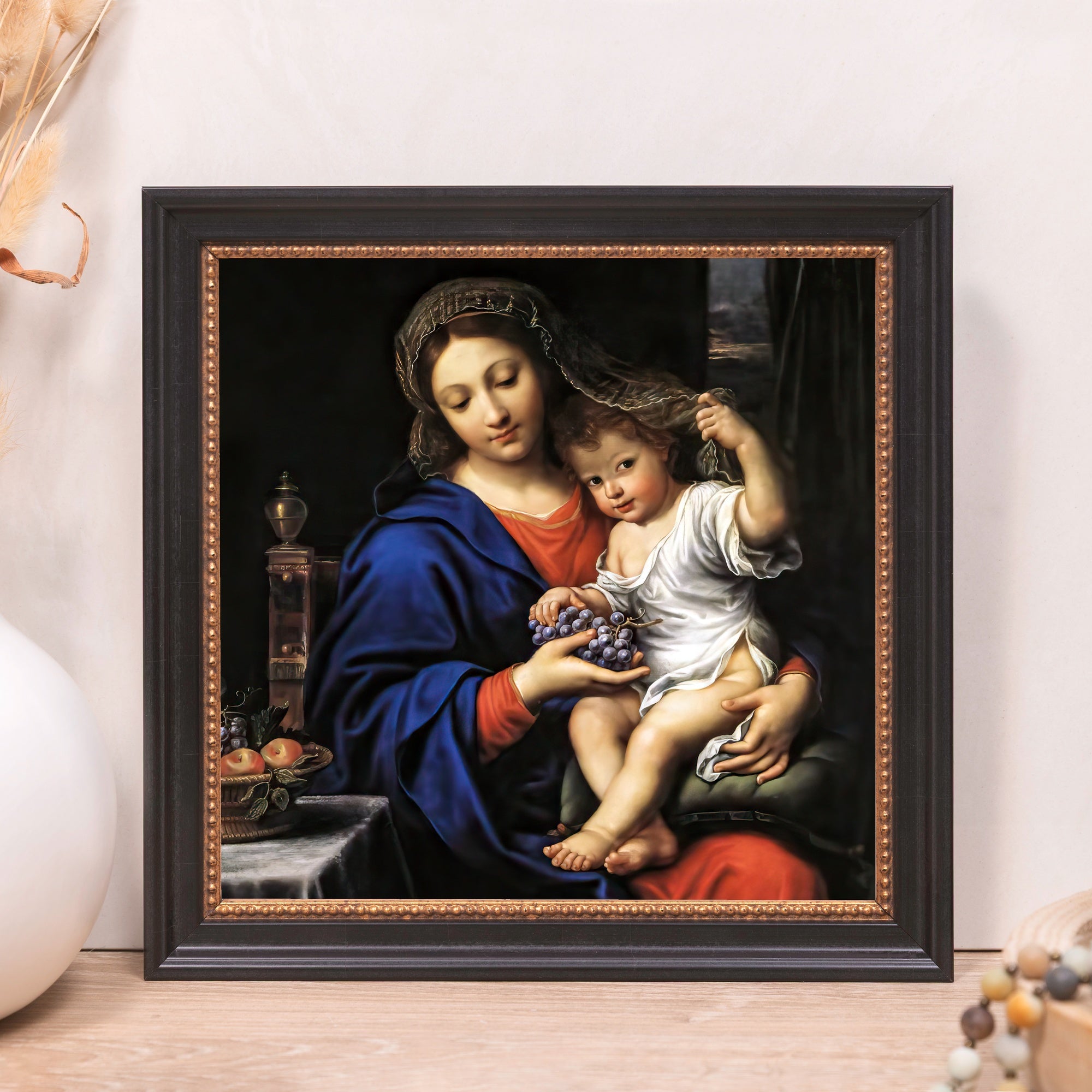 Framed print of Mary holding the child Jesus in blues and reds with a black and gold frame.
