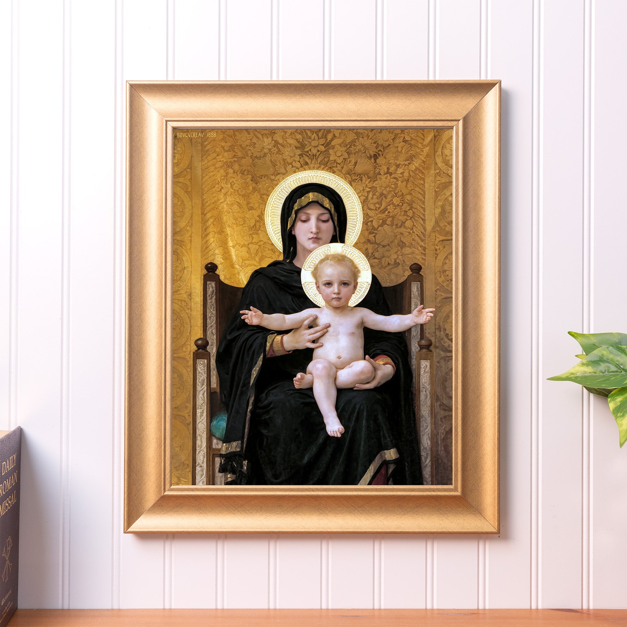 Framed painting of Mary and baby Jesus with halos, gold frame, on a wall.