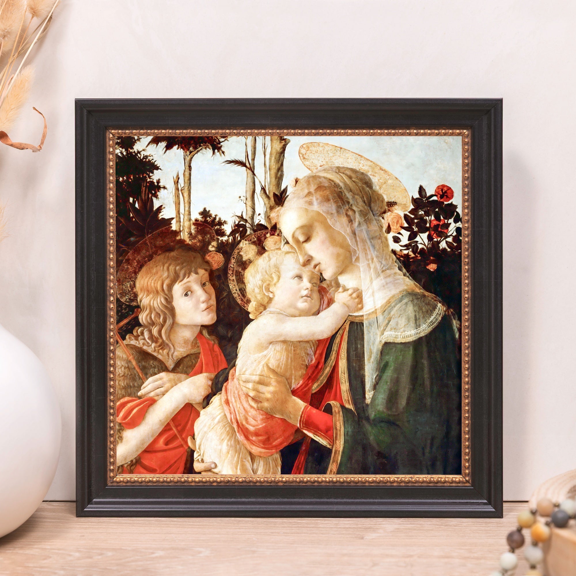 Framed print of the Madonna and child in a black wooden frame with a gold beaded accent.