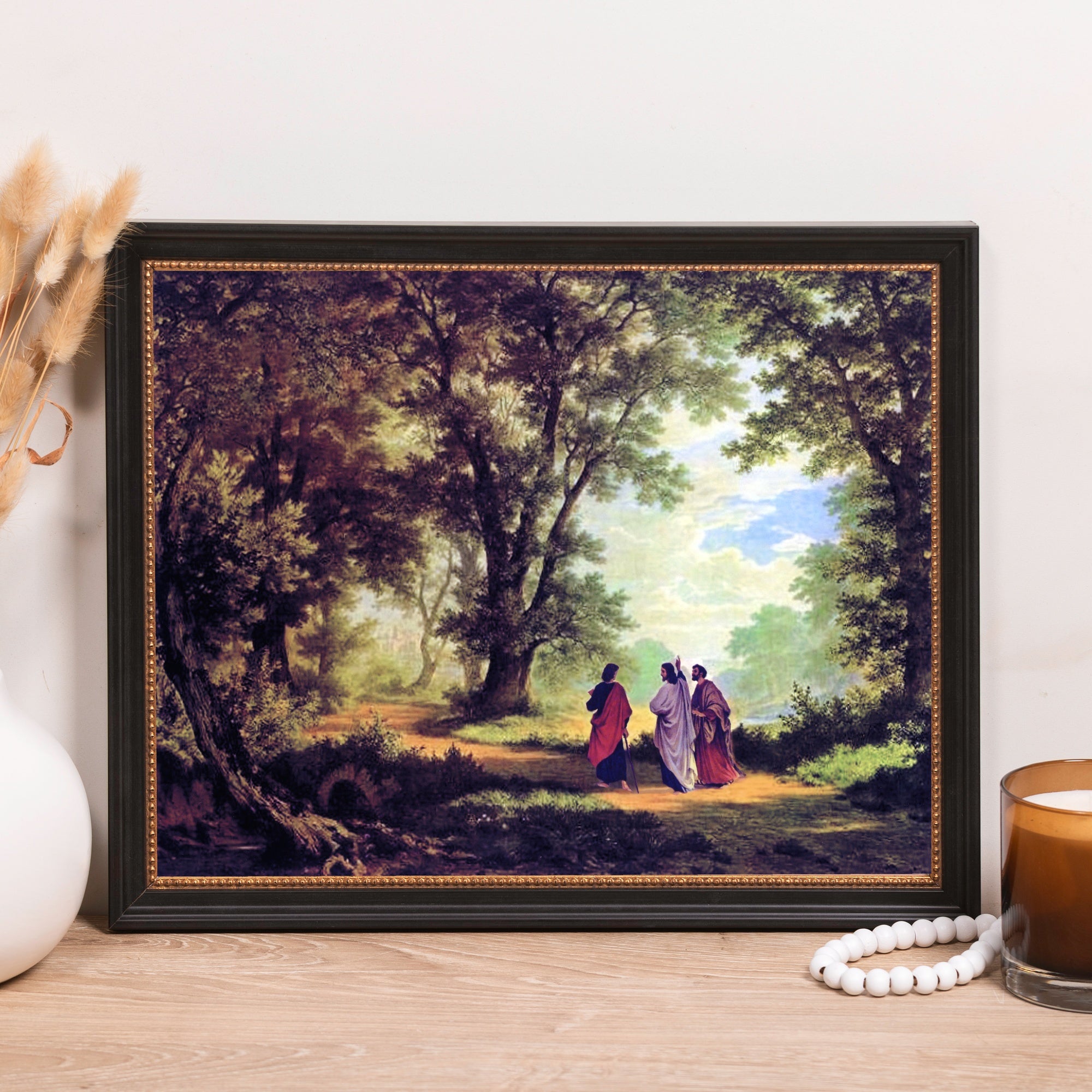 Framed print of Jesus on the road to Emmaus, warm colors, black frame with gold trim.