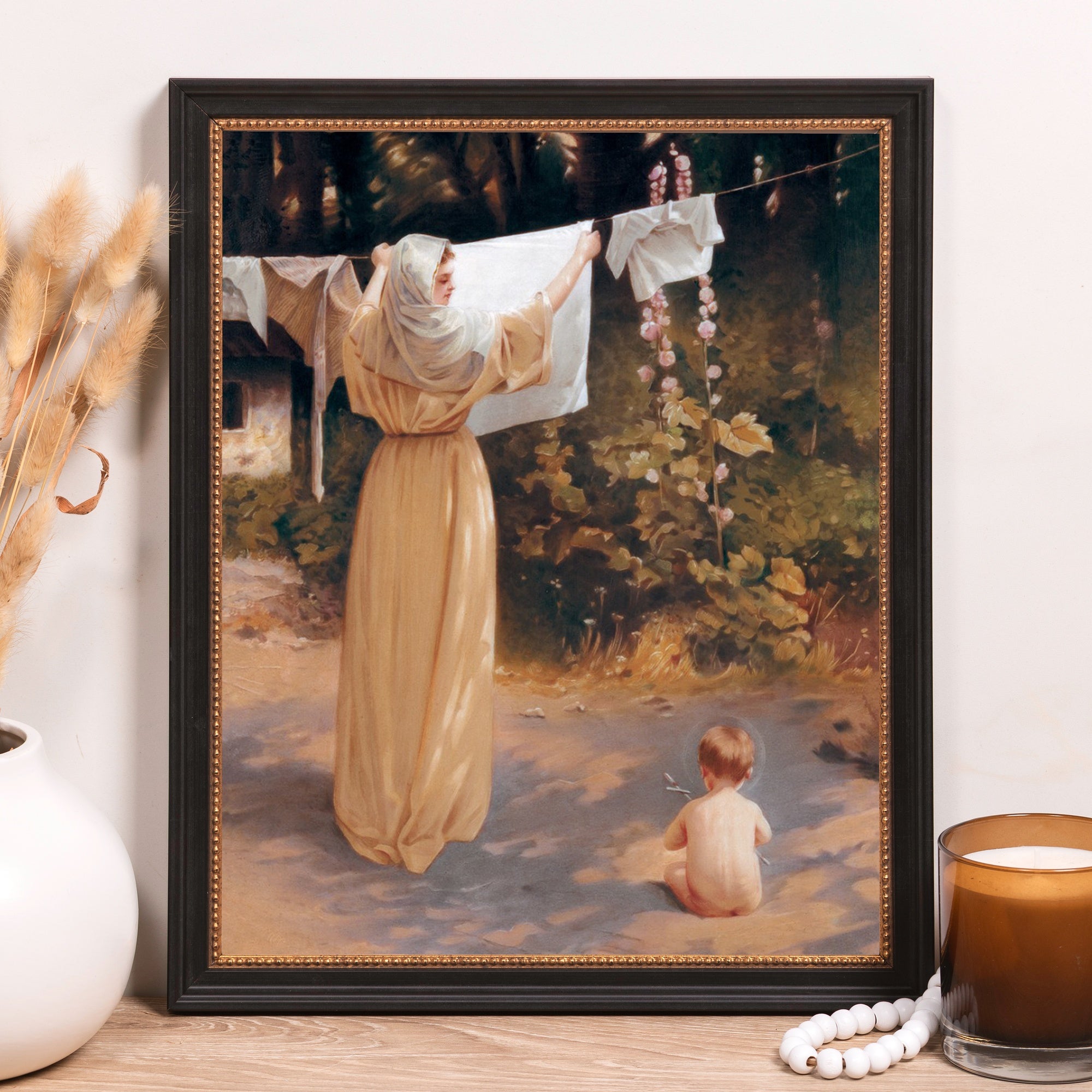 Framed print of woman hanging laundry with child.
