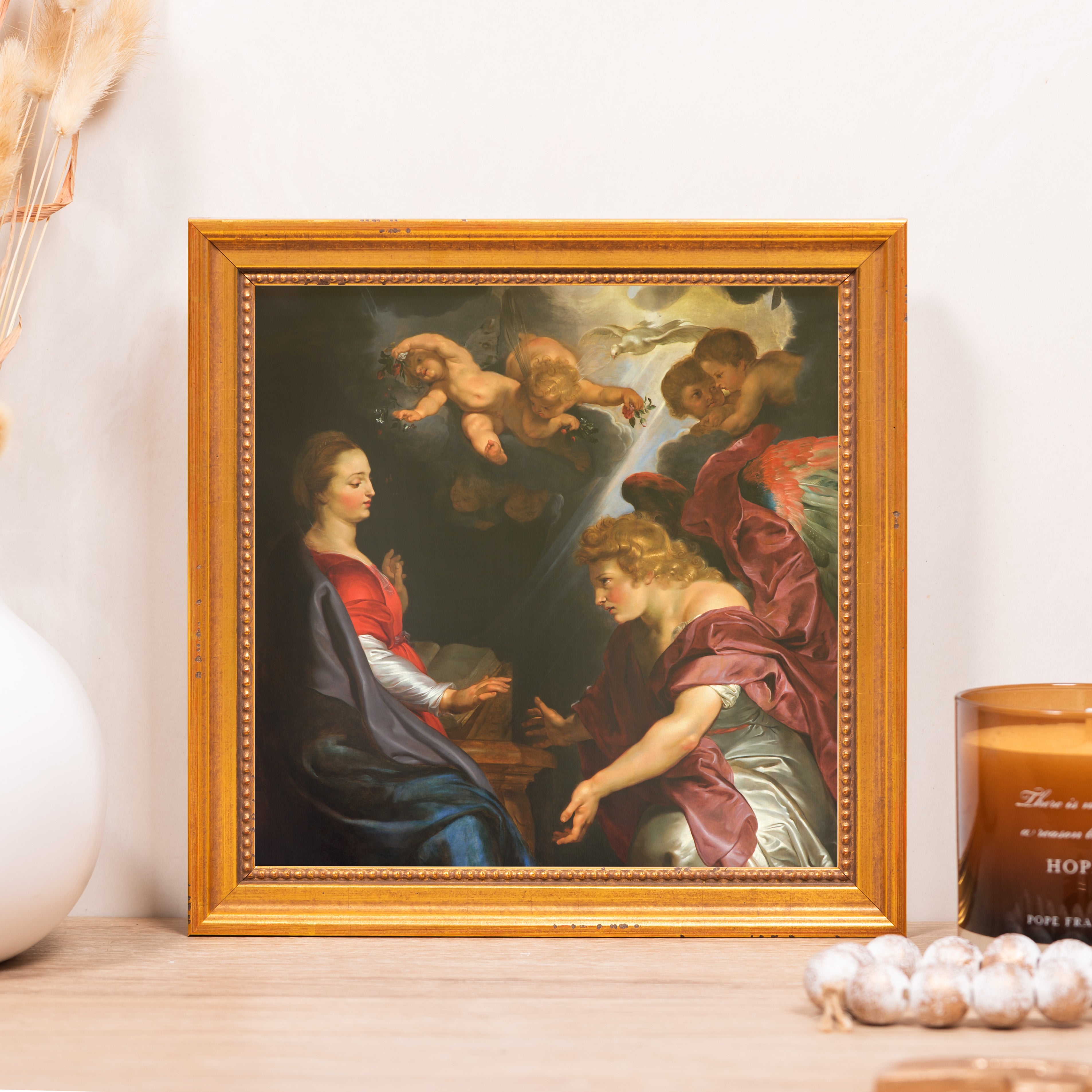Framed print featuring an angel in a red robe speaking to a woman, framed in ornate gold wood.