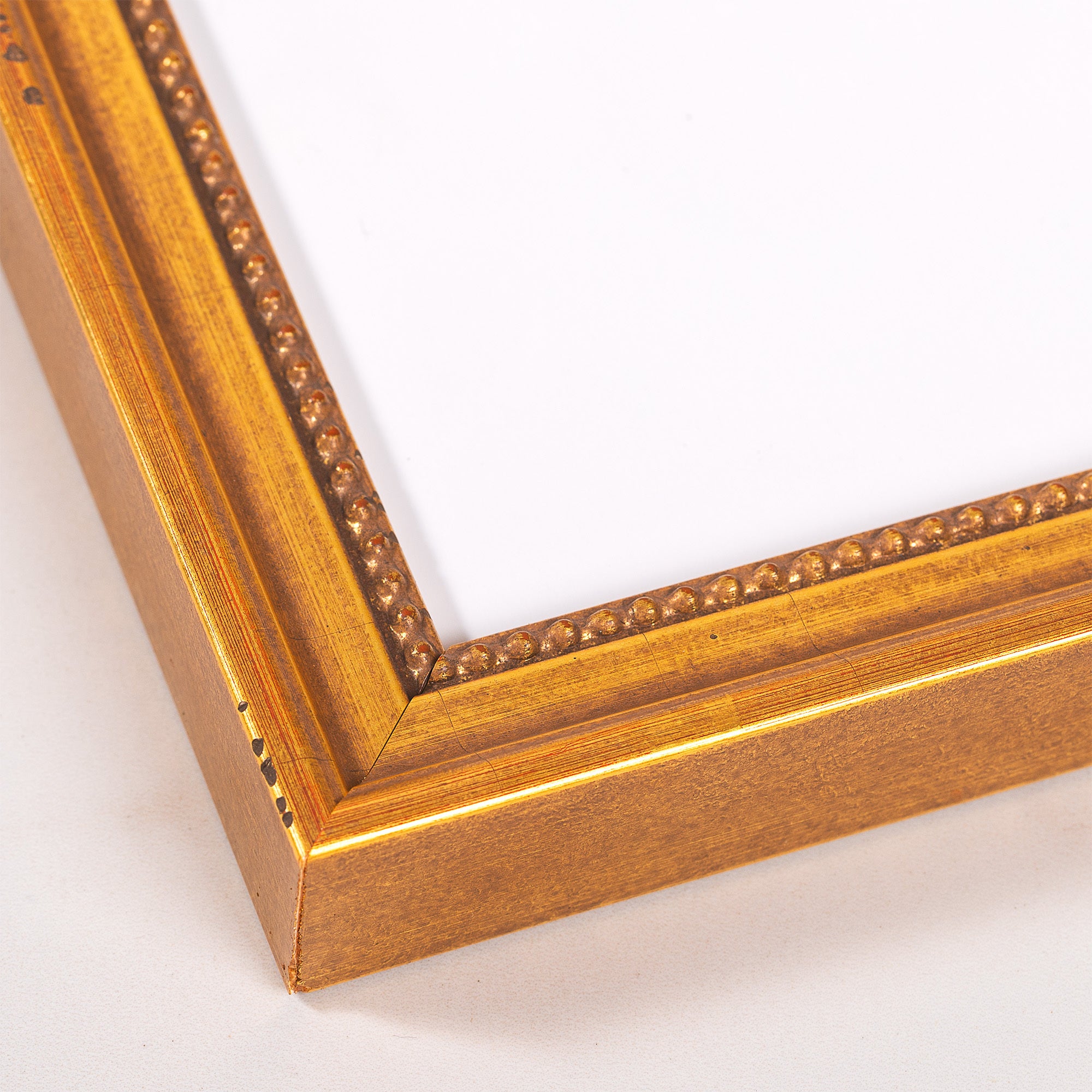 Gold-tone picture frame with beaded inner edge and wooden texture.