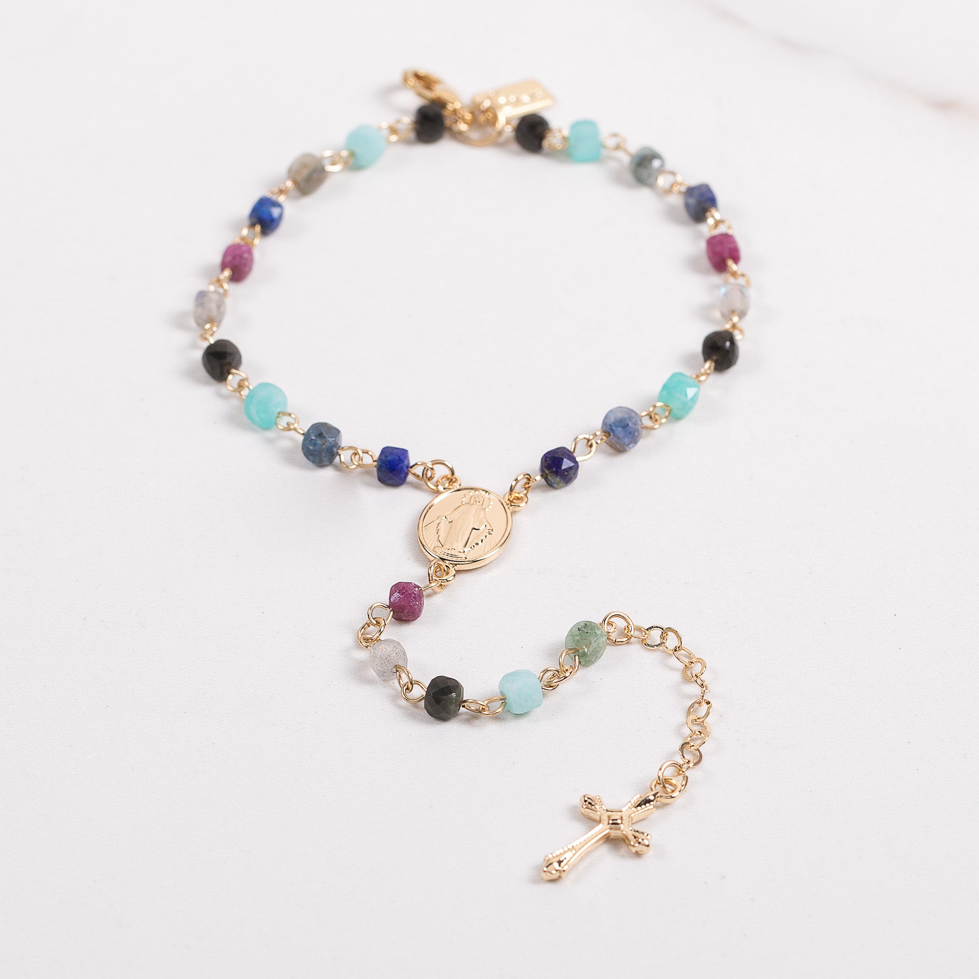Gold bracelet with multicolored beads and a cross pendant.