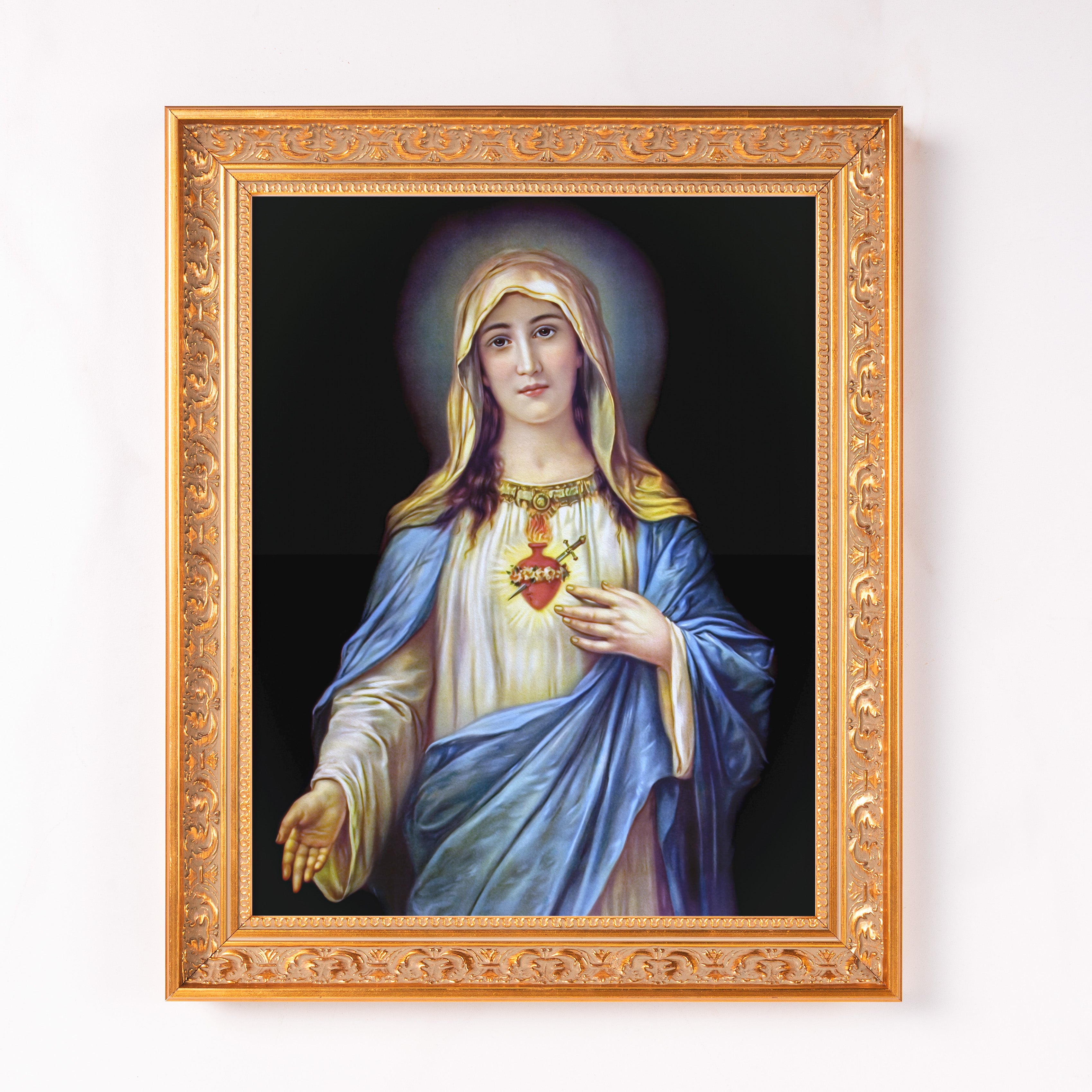 Framed portrait of Virgin Mary in ornate gold frame on wall.