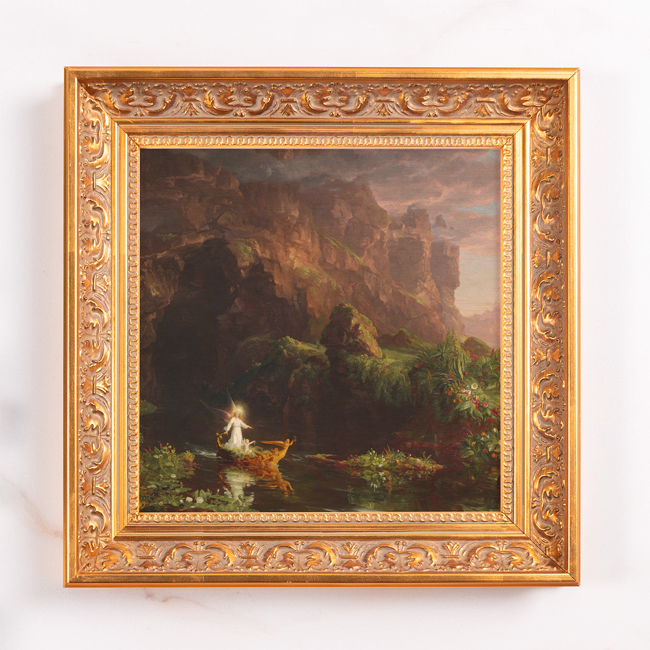 Framed Painting features an angel boating on a river surrounded by cliffs and plants in an ornate gold frame.
