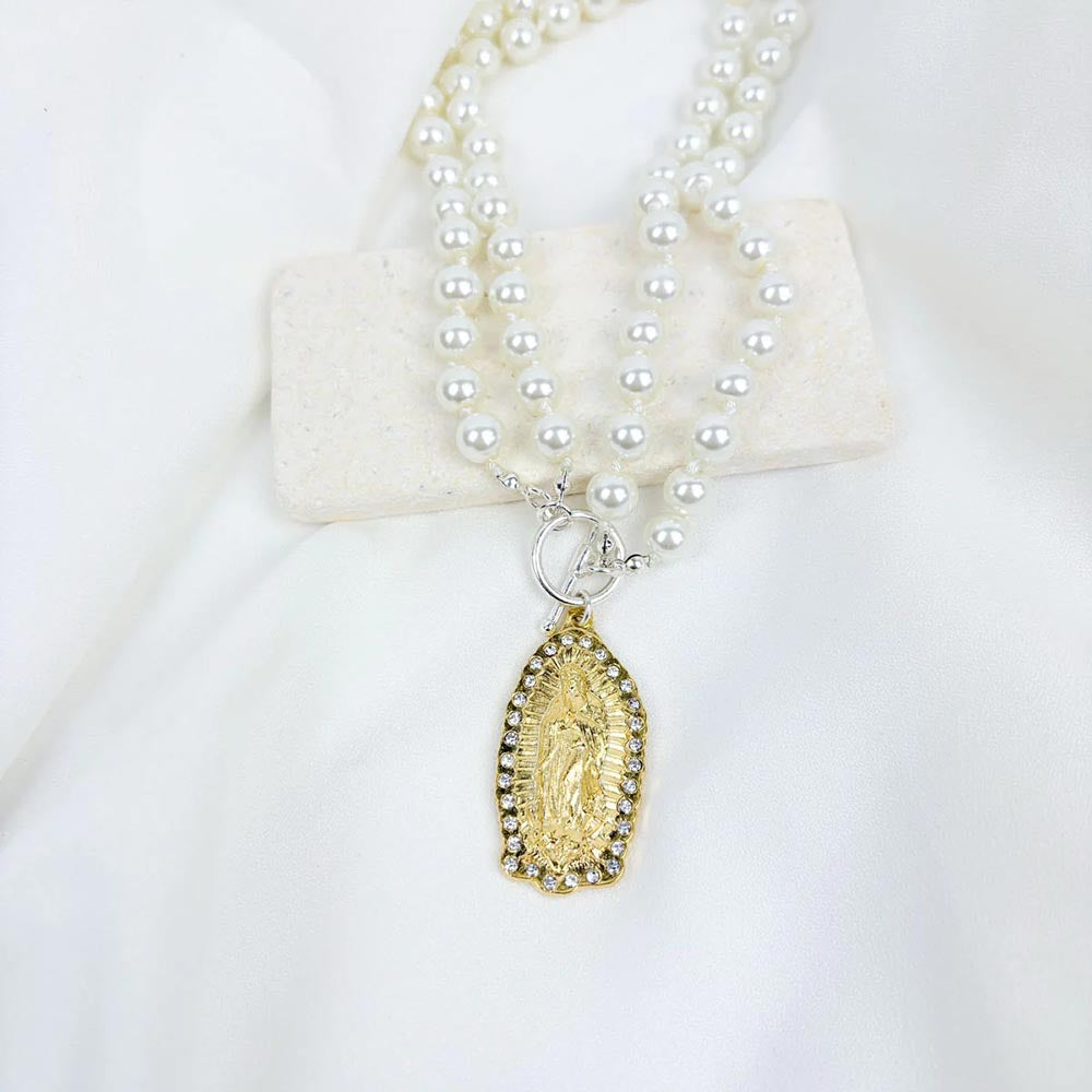 Pearl necklace with Virgin Mary pendant featuring gold filigree and rhinestones on a white background.