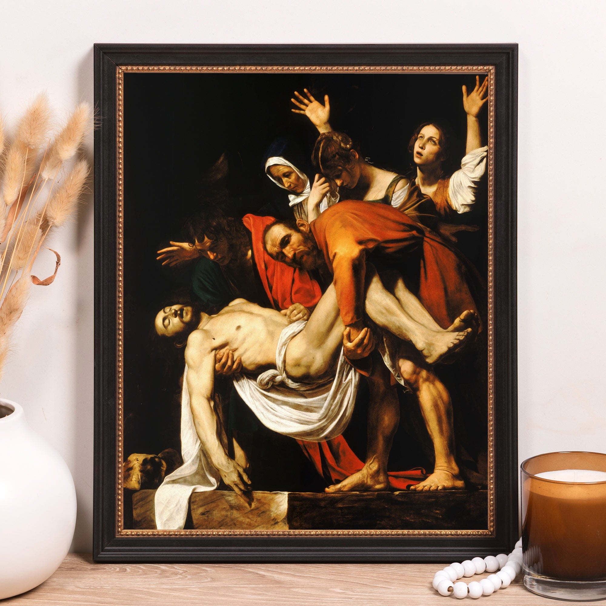 Framed reproduction of "The Entombment of Christ," a Renaissance painting in a black and gold wood frame.