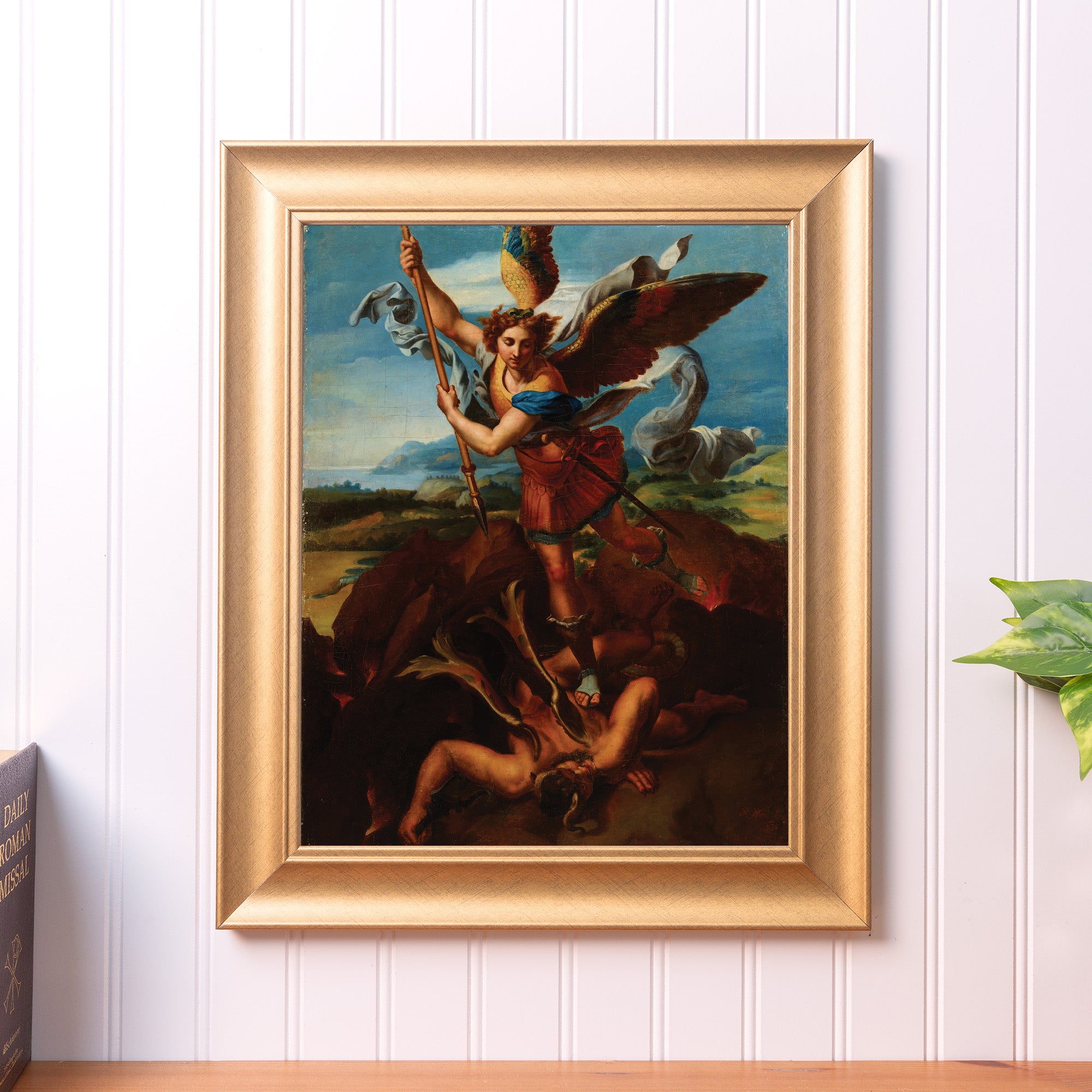 Framed painting of St. Michael defeating Satan in an ornate gold frame, depicting religious art.
