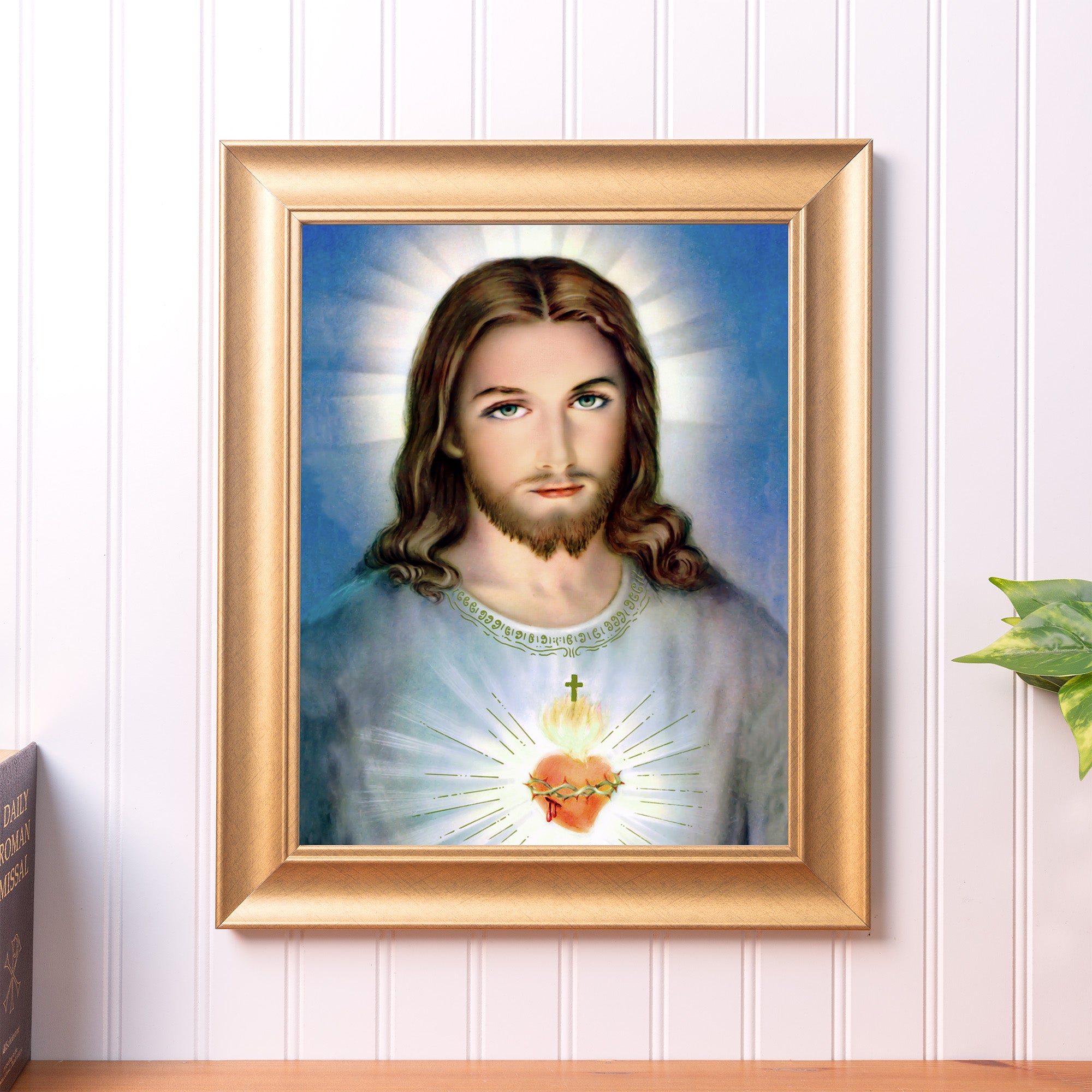 Framed Portrait of Jesus with the Sacred Heart in a gold frame, hung on a white wall.