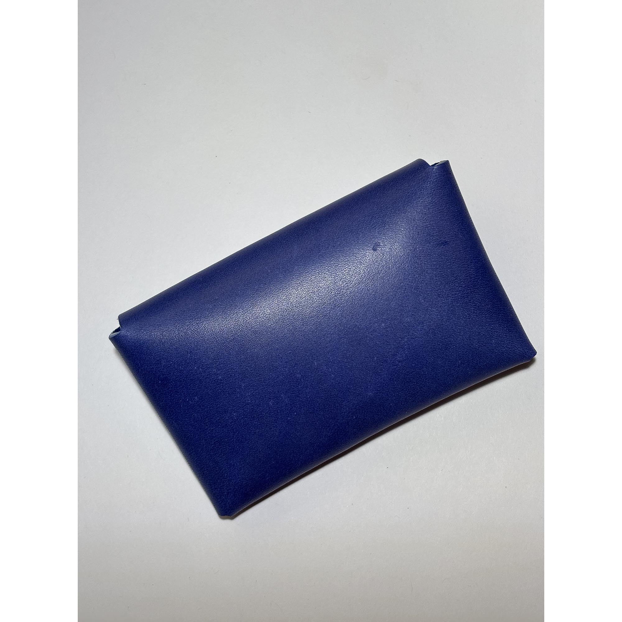 Blue, leather card holder with a minimalist design, lying flat.