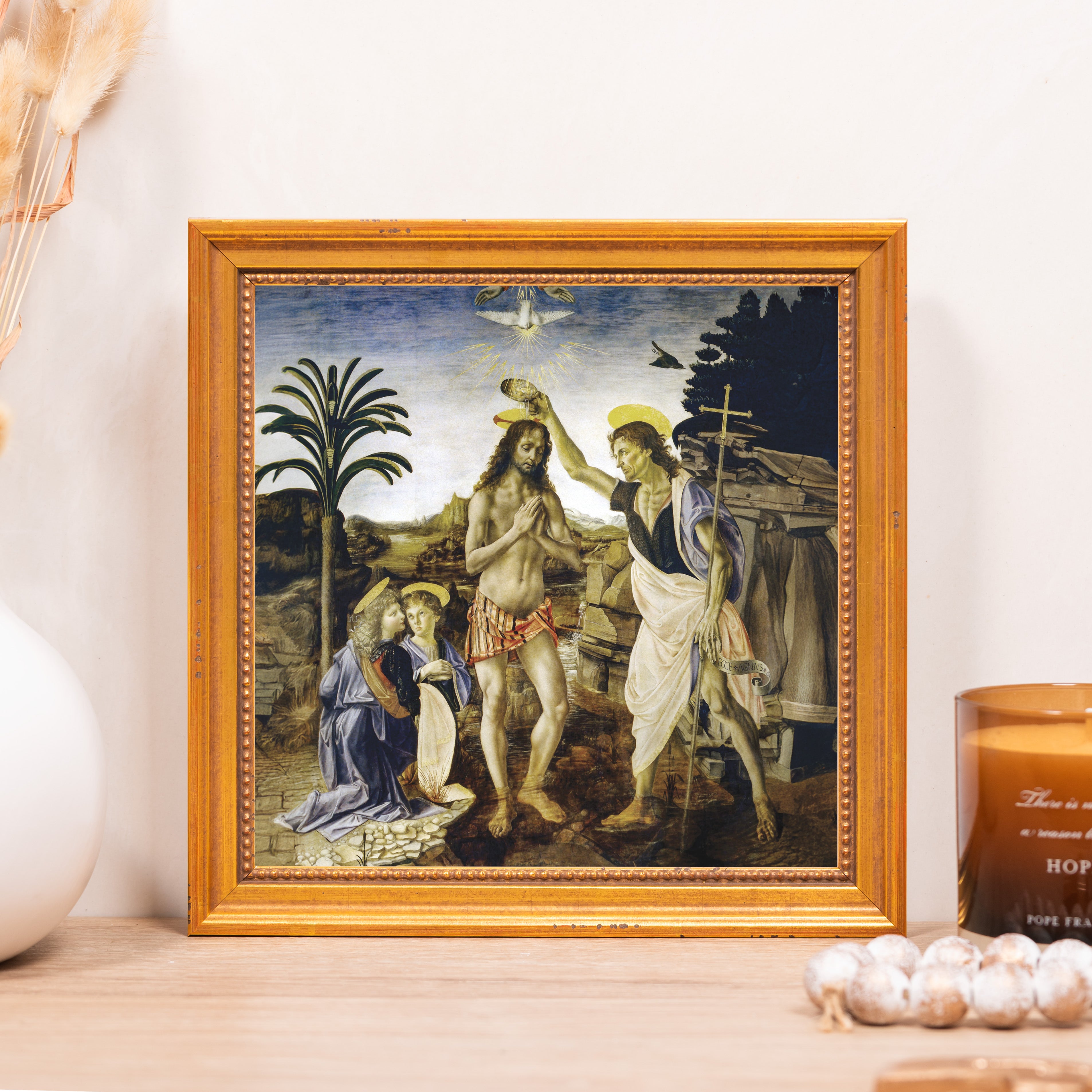 Framed artwork of Jesus' baptism with blue background and gold frame.