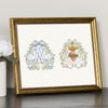 Framed floral art print with blue initial and sacred heart designs on cream paper.