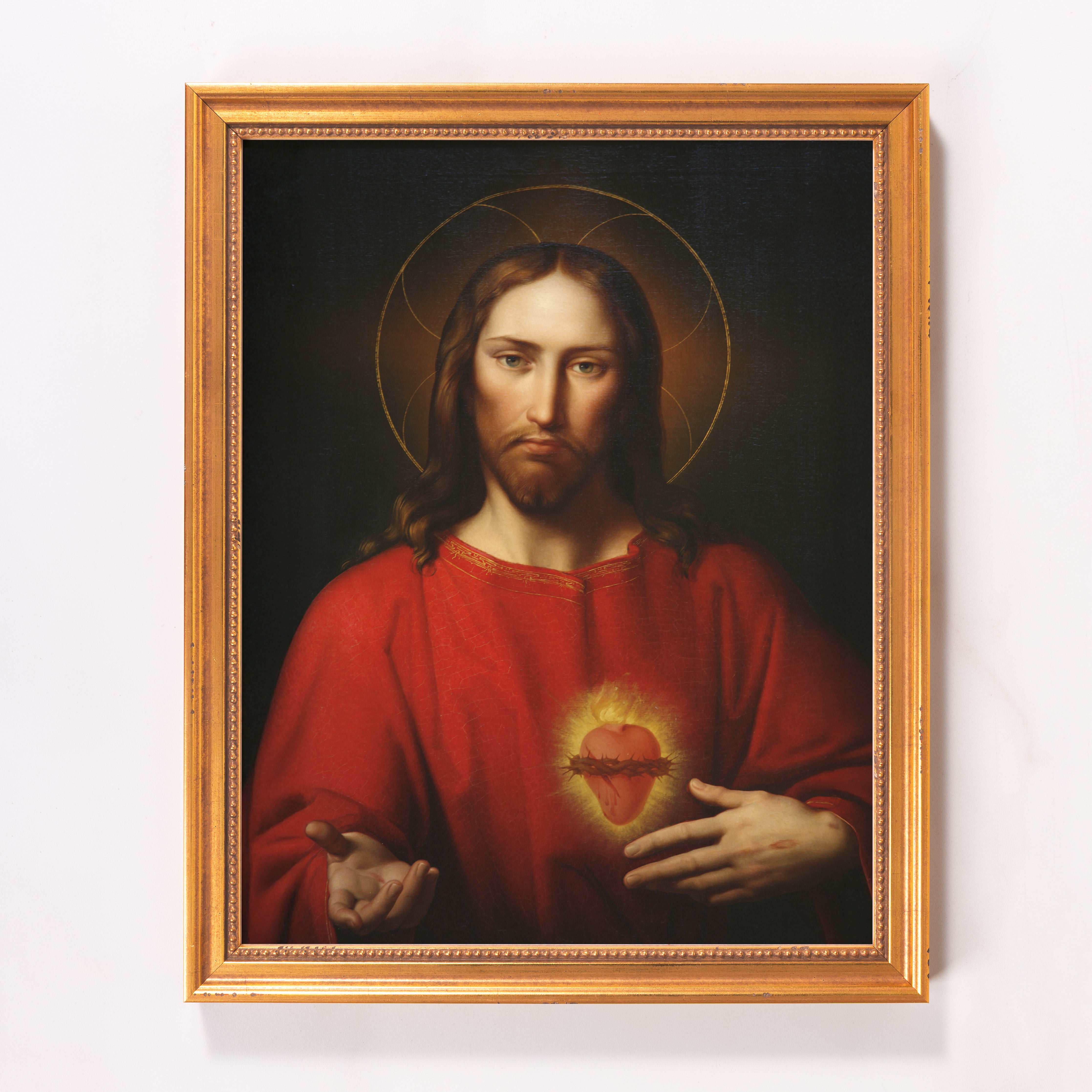 Framed painting of Jesus with a glowing heart, wearing red, with a gold halo and frame.
