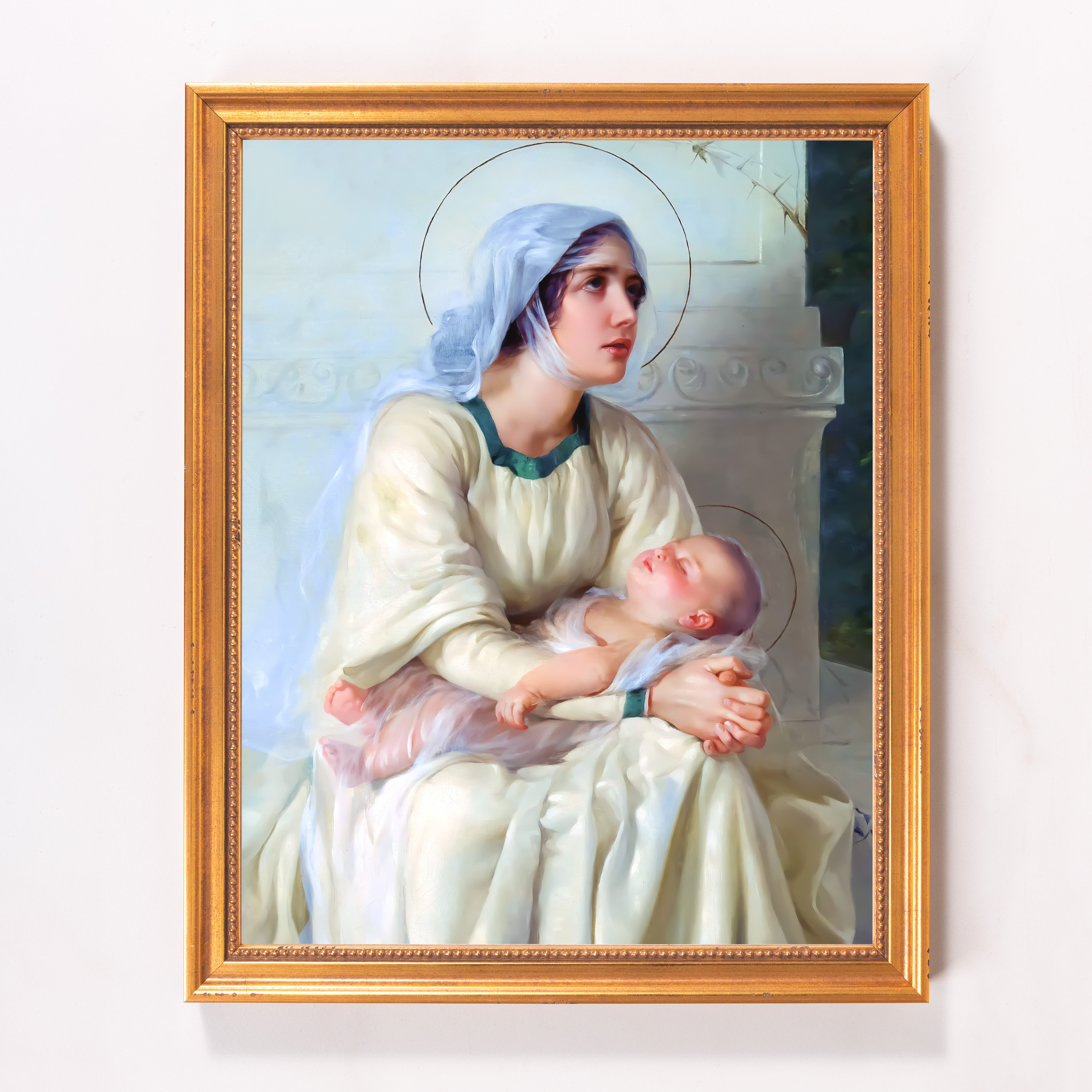 Framed painting of Madonna and Child in light robes with gold frame.