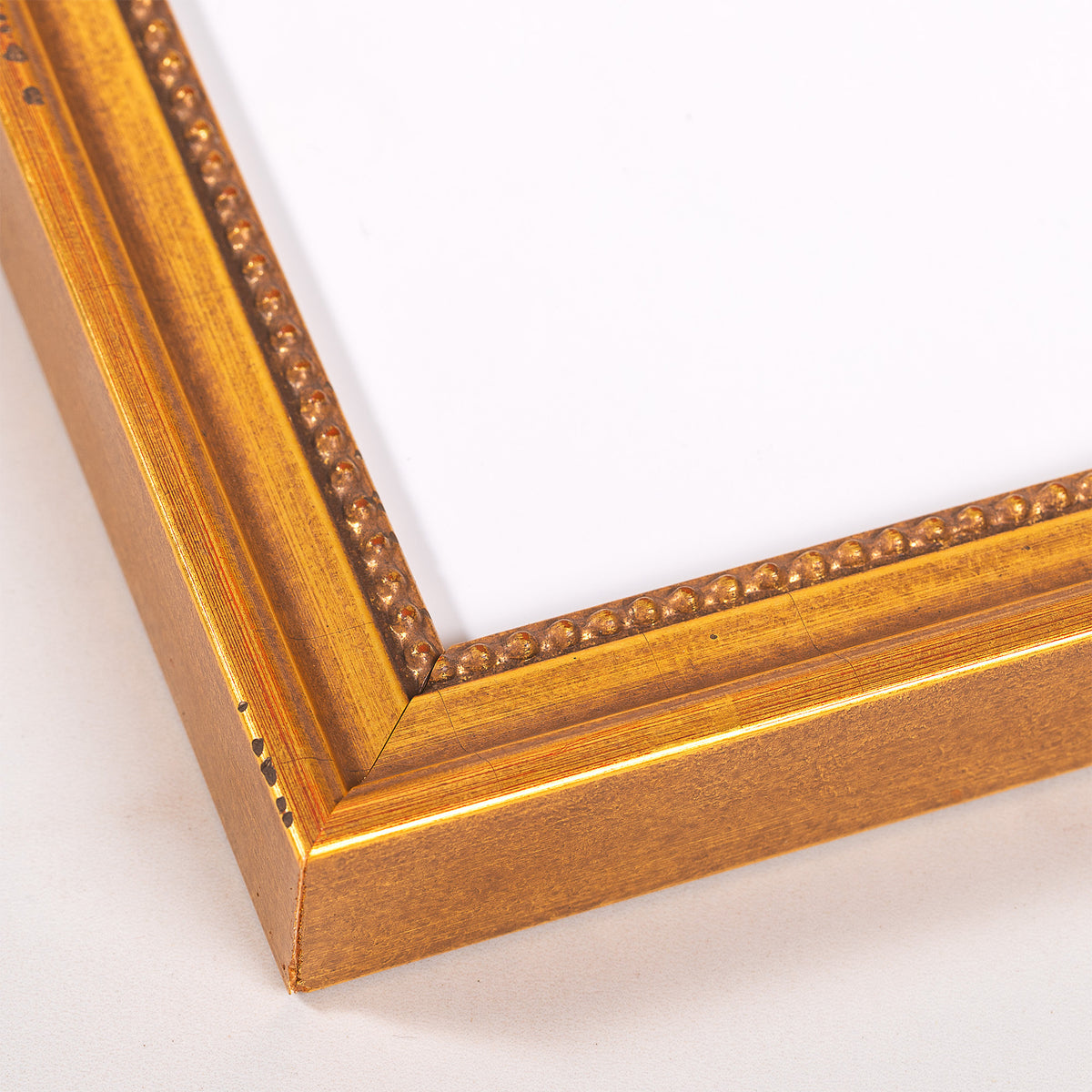 Gold-toned wood frame for art with raised beaded trim in an ornate style.