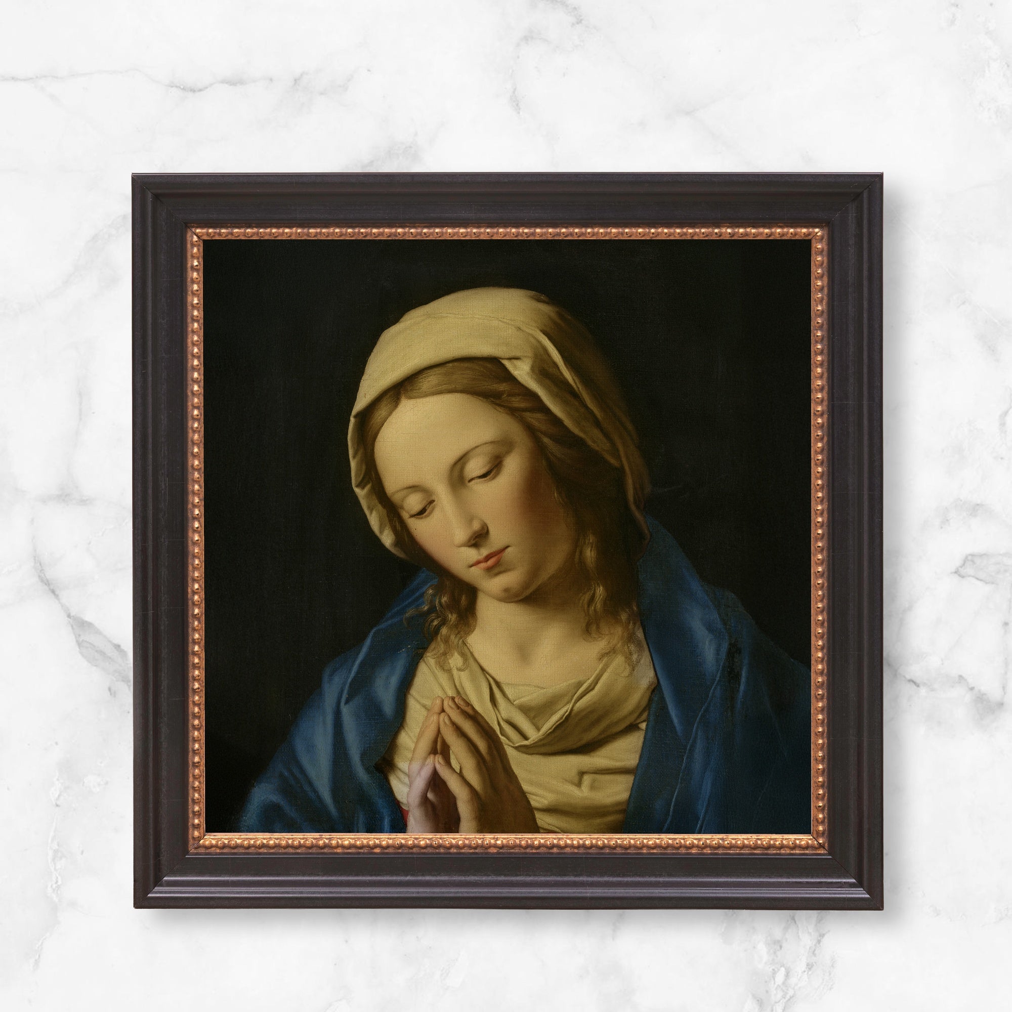 Framed painting of Mary, blue robe, tan head covering, hands folded in prayer, on canvas, traditional style.