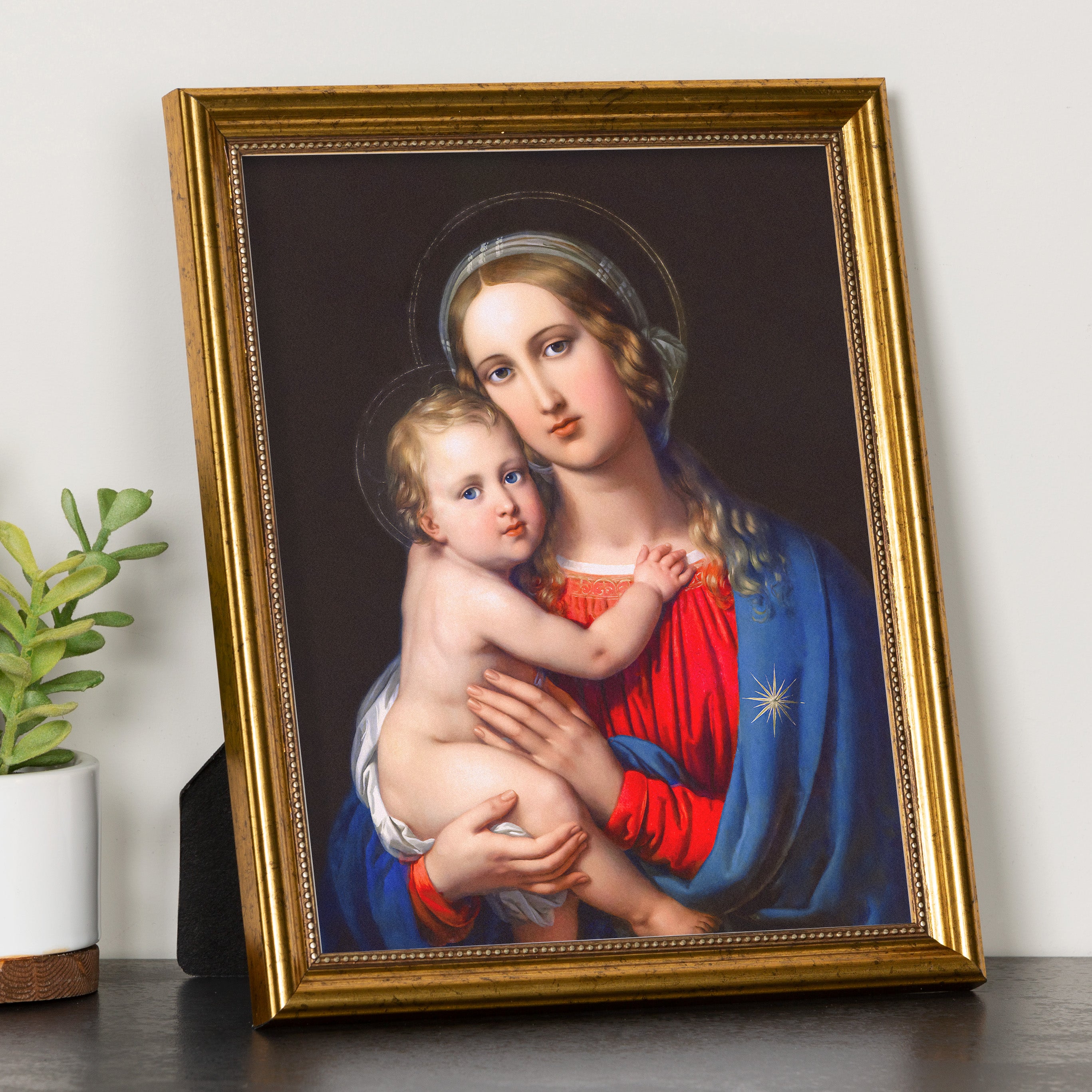 Framed artwork depicts a religious portrait of Mary and child in blue and red, gold frame.
