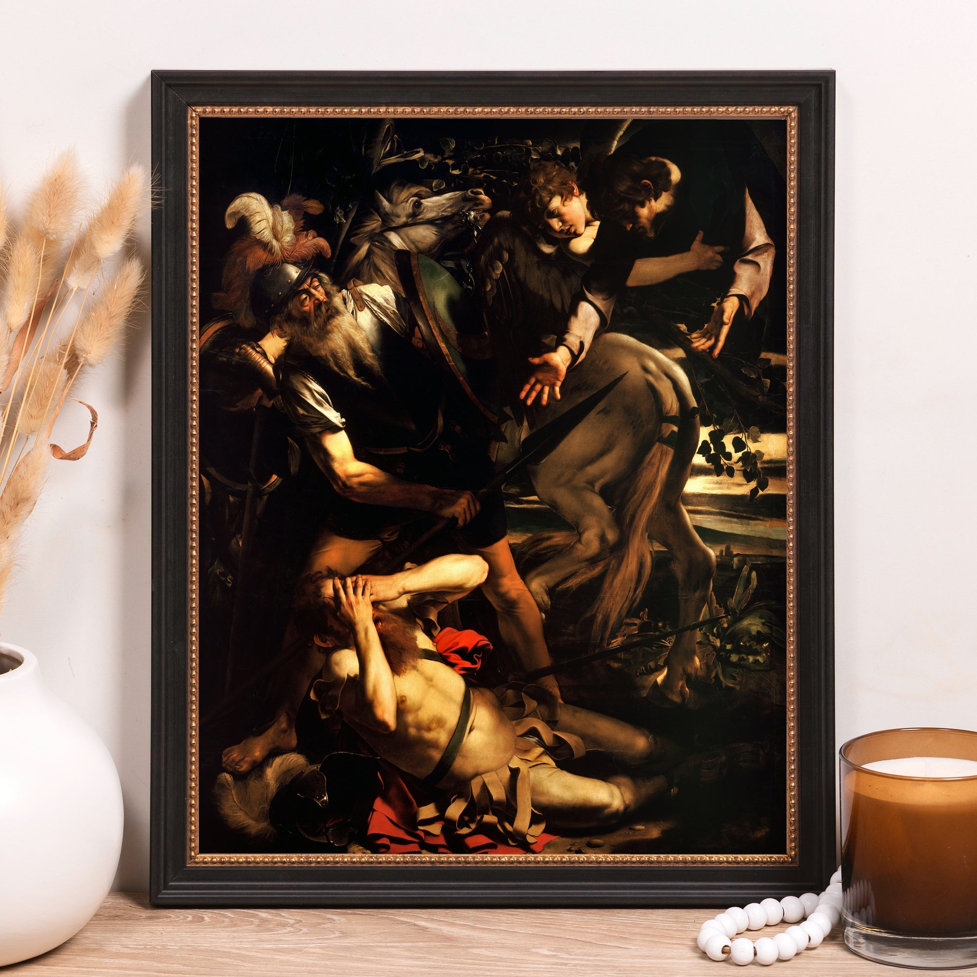 Framed reproduction wall art depicting a Baroque-style battle scene in muted tones, featuring a black frame with gold accents.