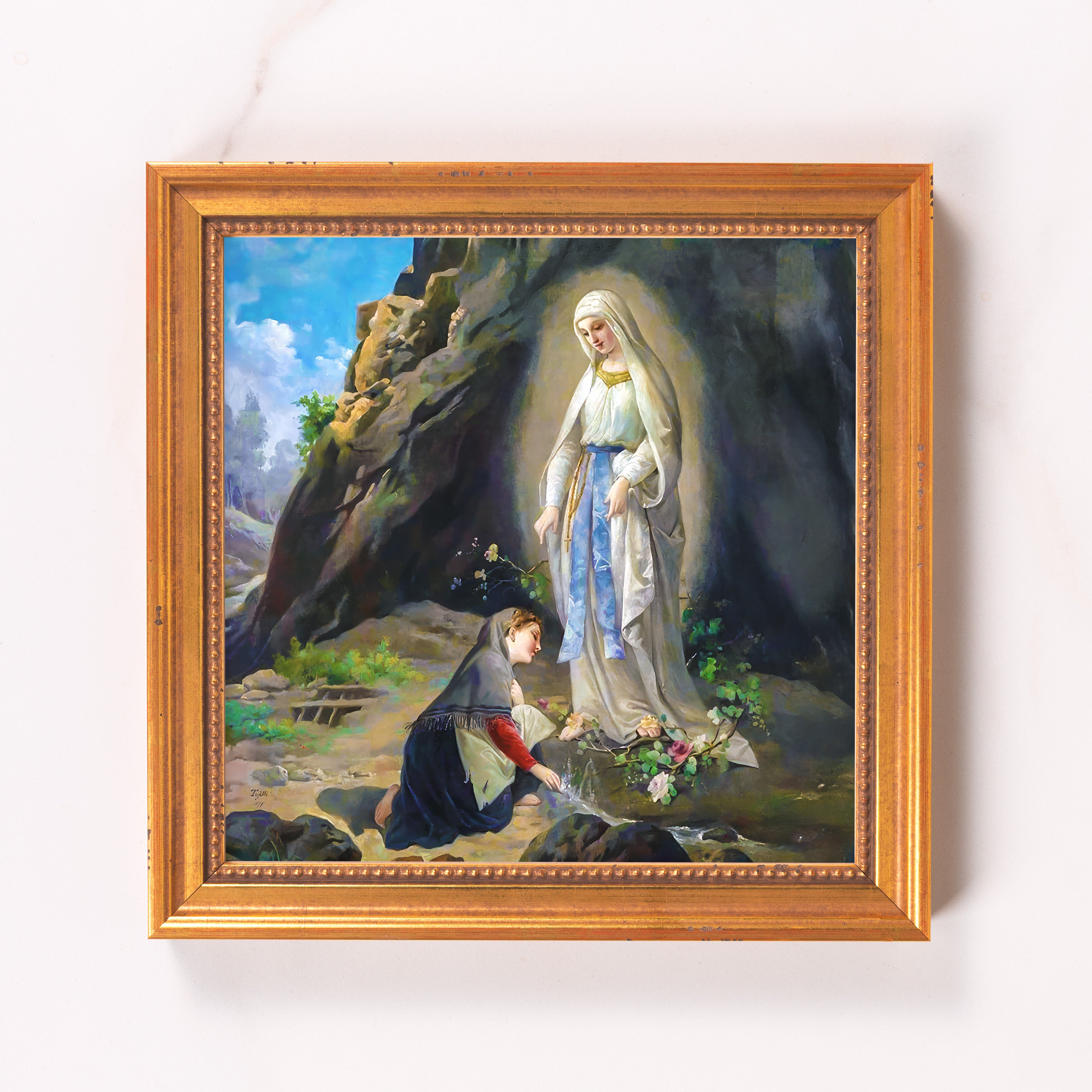 Framed print of a Lourdes scene with a gold-toned frame depicts Mary and Bernadette Soubirous in an outdoor setting.