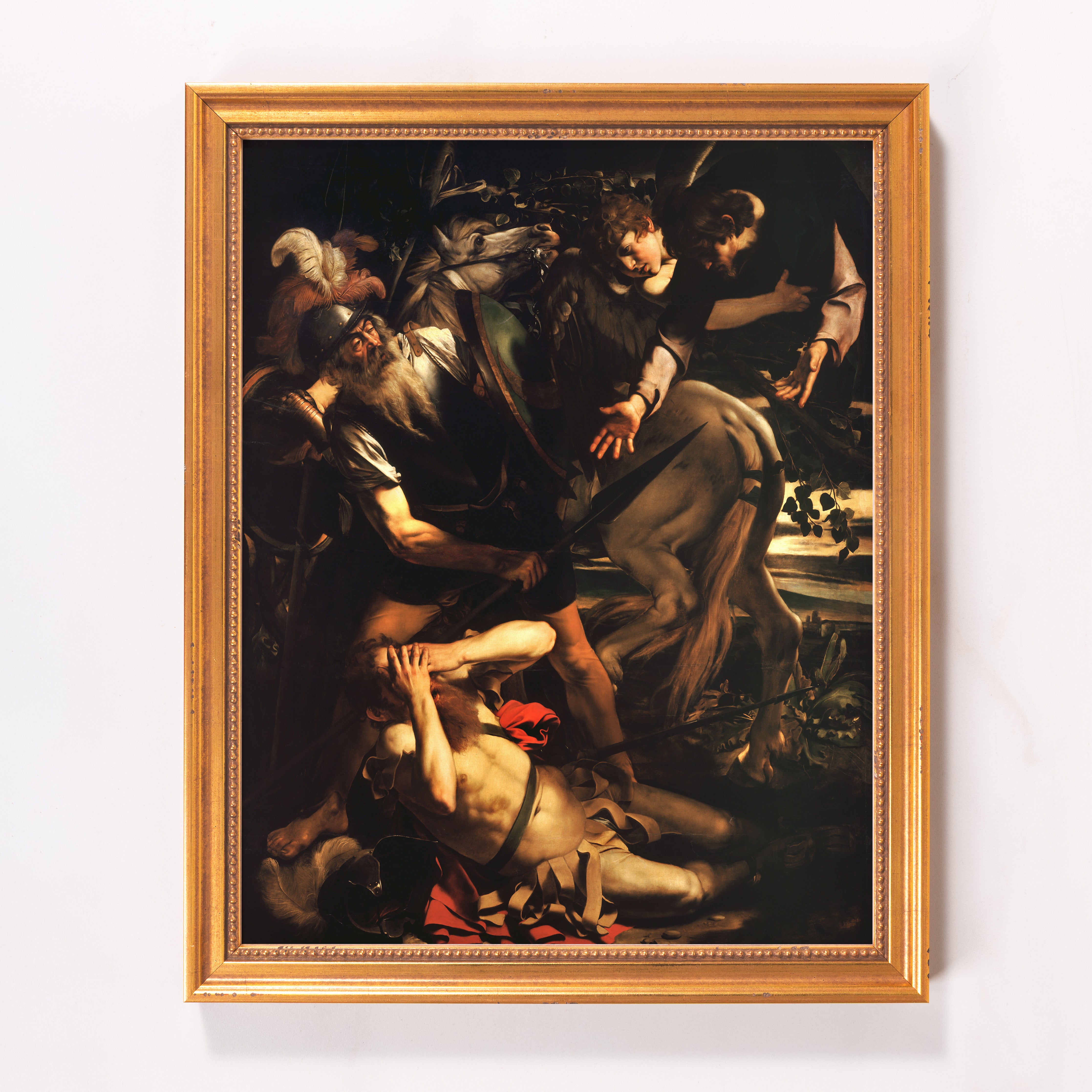 Framed Caravaggio print depicts dark, baroque art with gold frame.