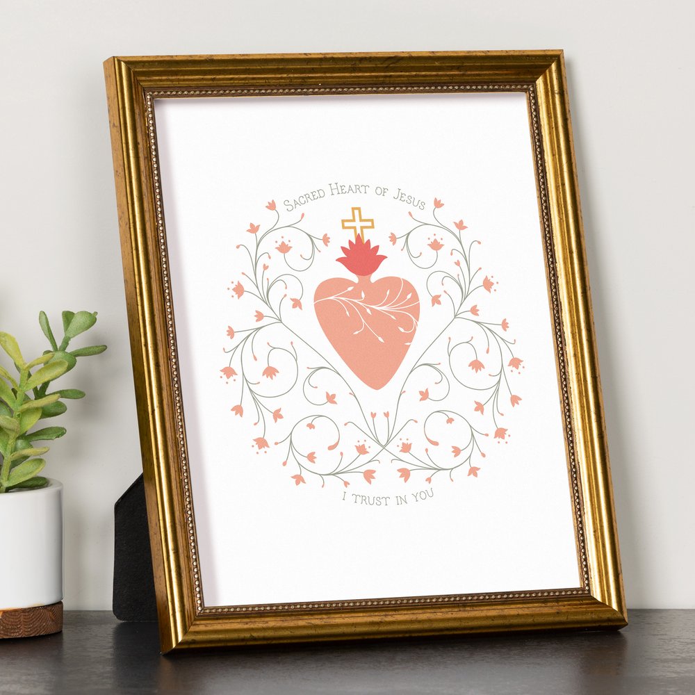 Framed print of the Sacred Heart of Jesus with a golden frame, peach heart, and floral design on a white background.