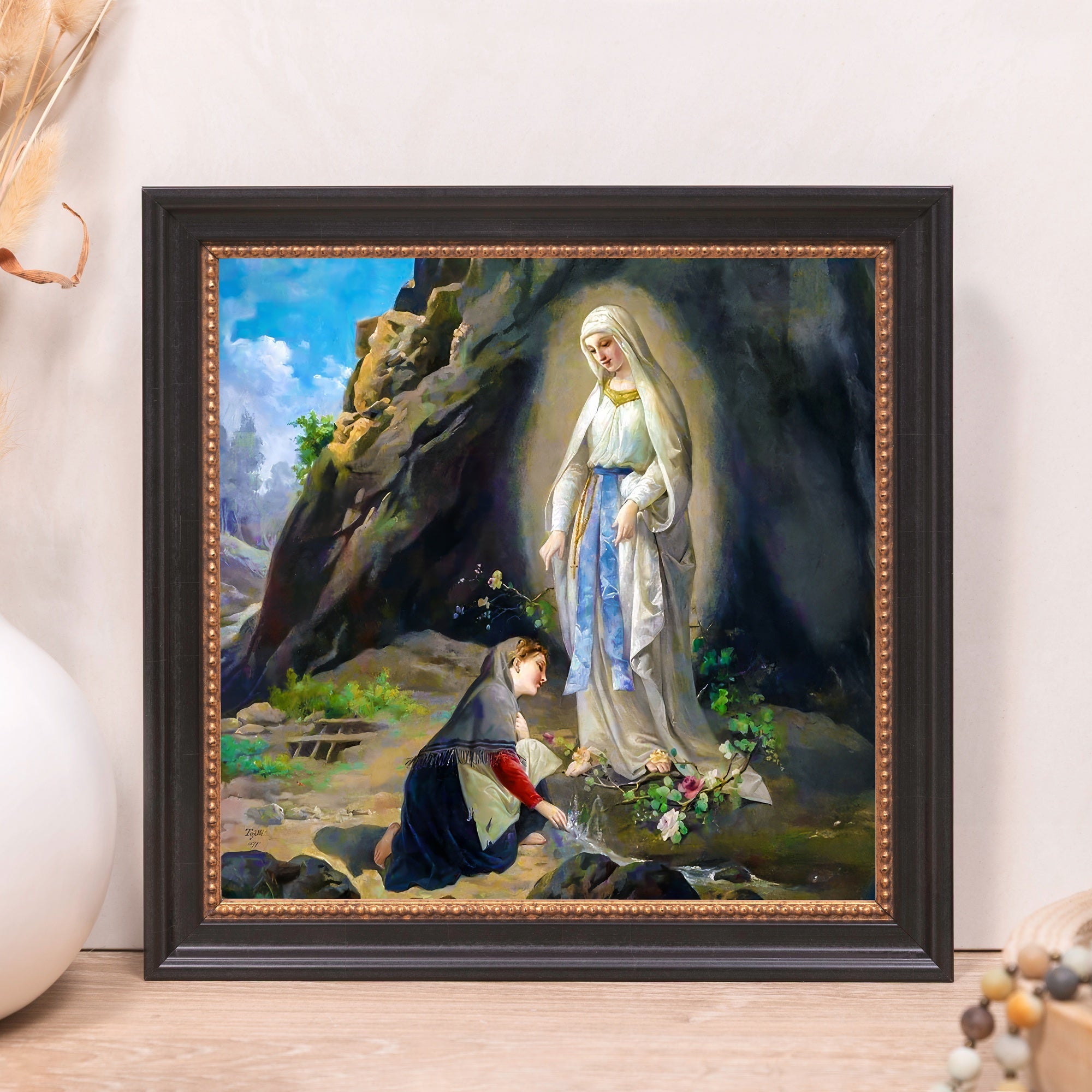 Framed Lourdes painting depicts Saint Mary appearing to a girl in a rocky grotto; black frame with gold accents.