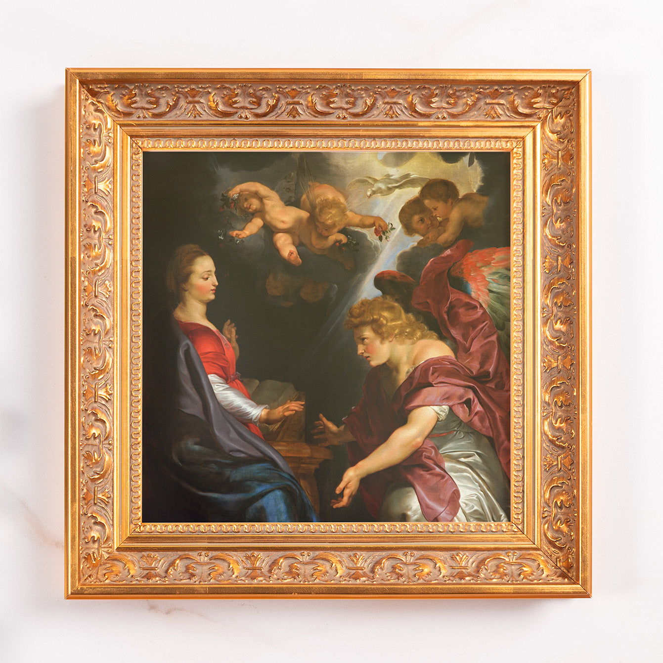 Framed painting of the Annunciation with cherubs in a decorative gold-tone wood frame.