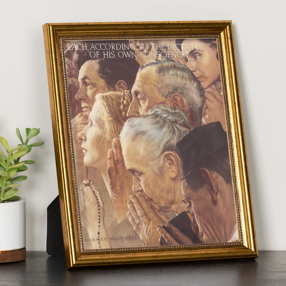 Framed print of a Norman Rockwell painting, depicting praying people, with a gold frame and black stand.