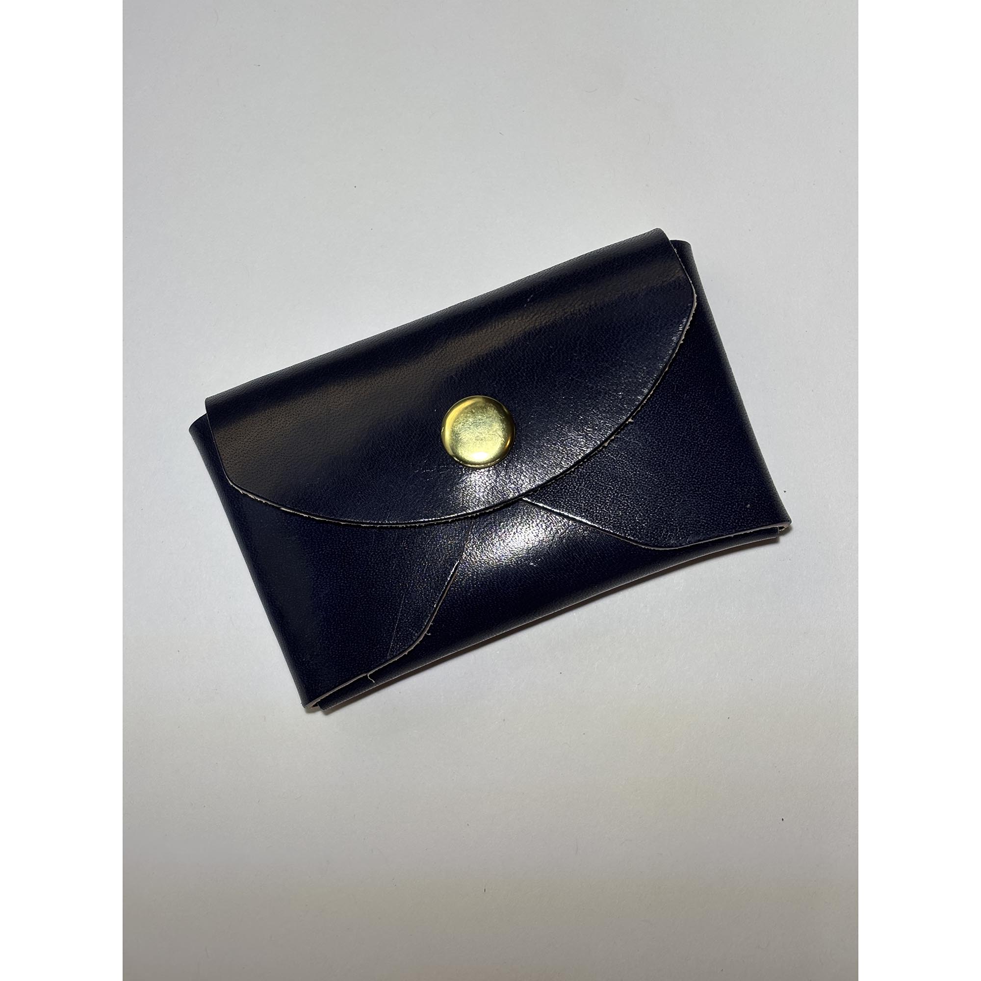 Navy leather card wallet with brass snap closure.